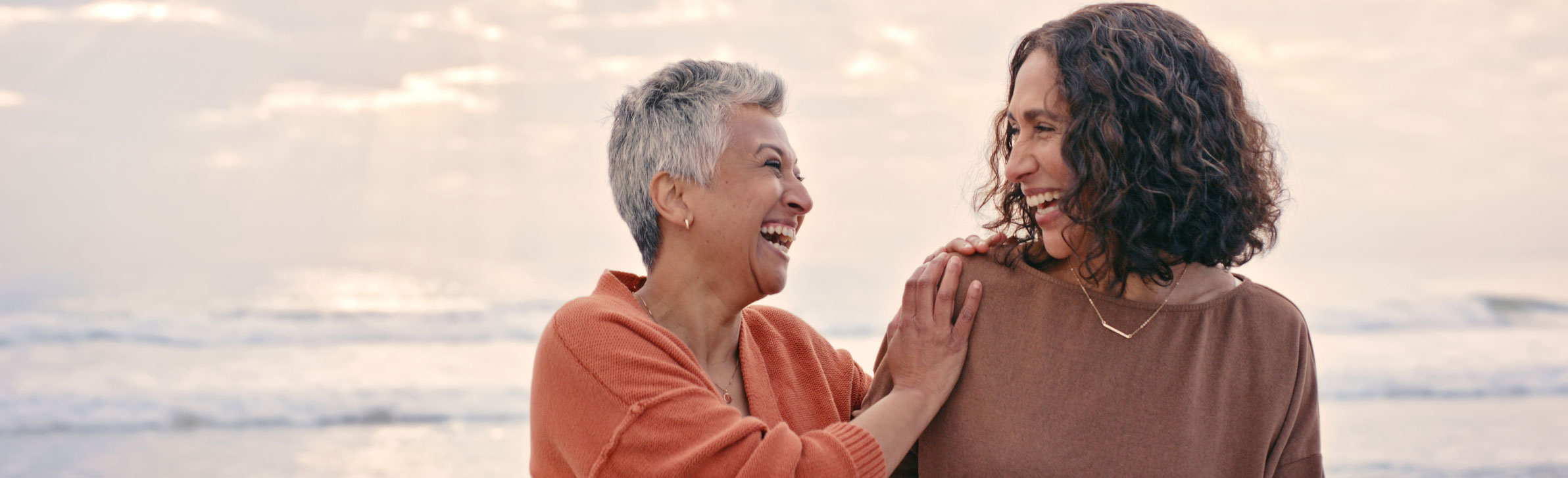 Mother and daughter laughing while walking on the beach