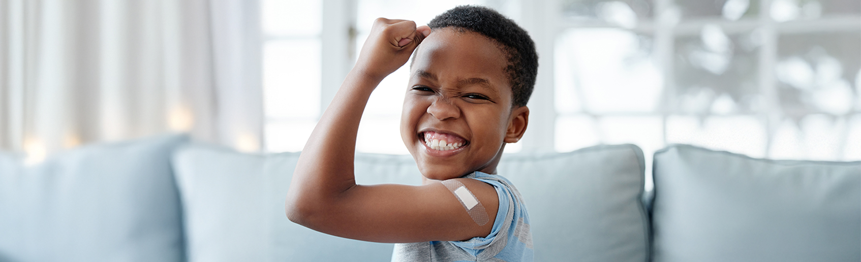 smiling child proudly showing bandaid on his arm