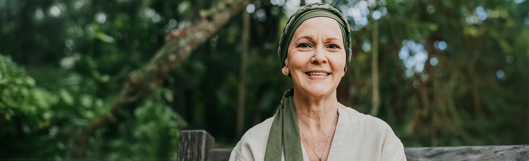 Woman sitting outdoors on a wooden bench in a peaceful, natural setting. 