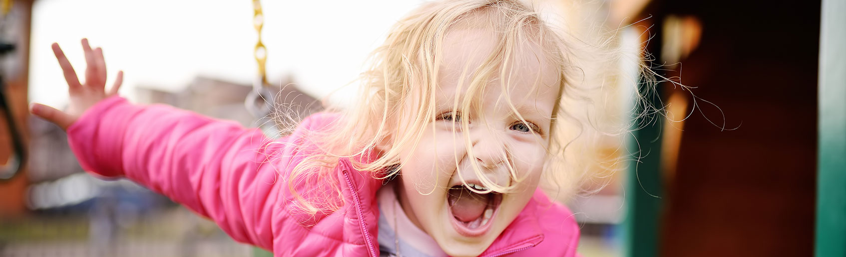 Smiling child playing on a playground swing